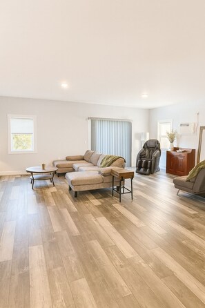 A spacious living room with a large L-shaped sectional sofa, a round coffee table, and a leather armchair. - River View family home (Winterport)