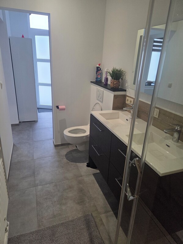 A modern bathroom with a toilet, sink, and shower. - Magnificent 2-bedroom apartment (Givet)