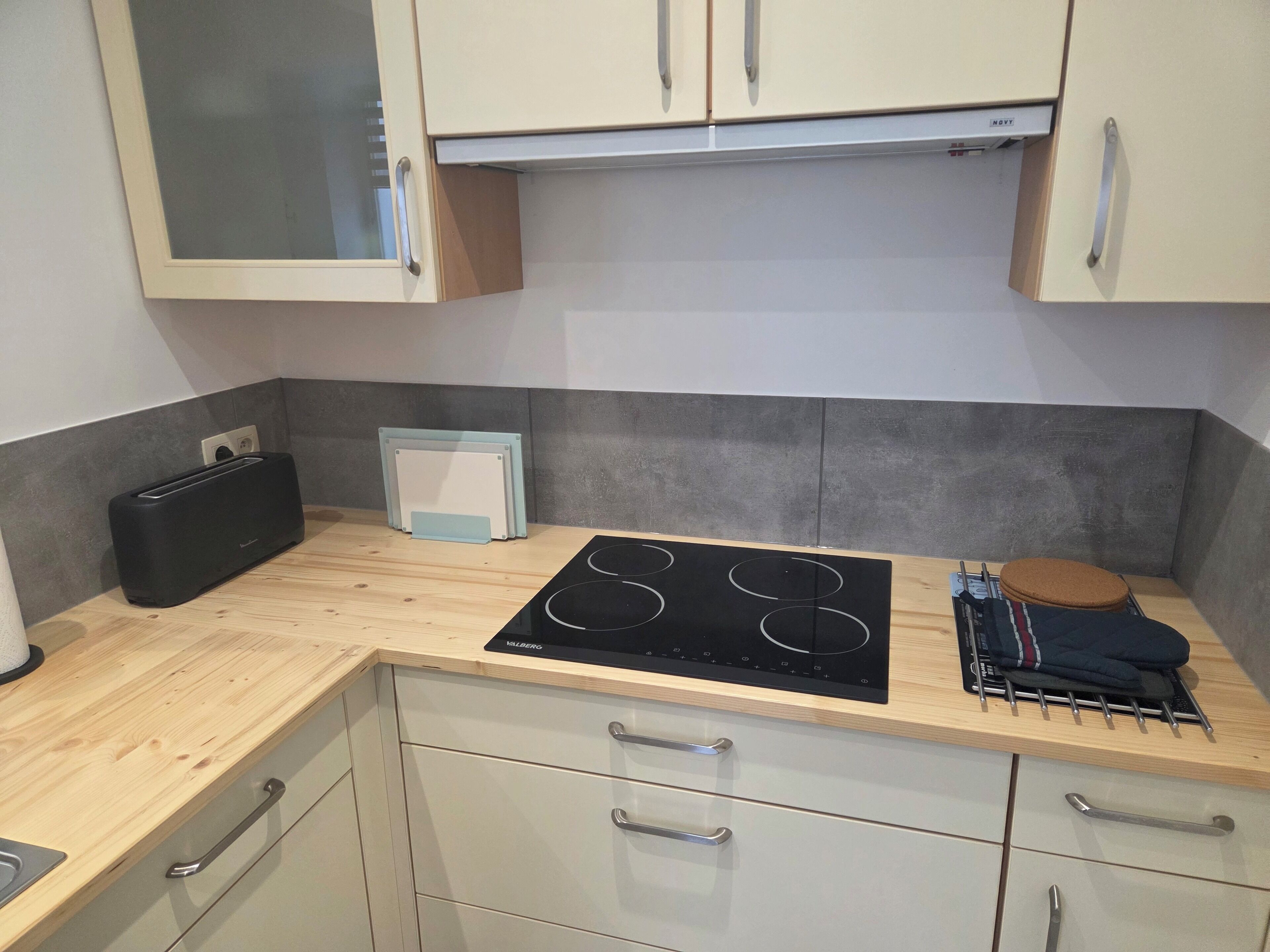 A compact kitchen with a built-in stove, a toaster, and a small cabinet.