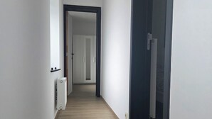 Kapea käytävä, jossa on puulattia ja valkoiset seinät.