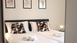 A hotel room with two beds, white linens, geometric patterned pillows, and artwork on the wall. - Tuscany Best Point [30 min by train to Florence] (Stazione)