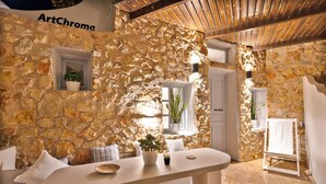 A stone-walled room with a white bar, a potted plant, and a white towel rack. - ArtChroma House (Santorini)