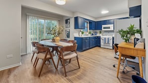 A modern kitchen with blue cabinets, a wooden dining table, and a large window. - Spacious 4BR Home Family & Pet-Friendly  2 Living Rooms + Game Fun in Plainfield (Plainfield)