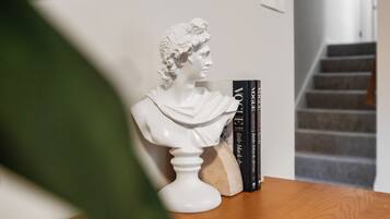 Een borstbeeld op een houten tafel, met boeken ernaast.