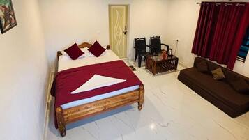 A bedroom with a bed, a sofa, a wooden ceiling, and a door.