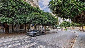 A street lined with trees and a parked car.