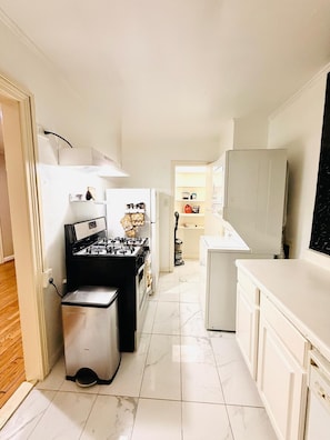 A narrow kitchen with a stove, oven, and a small trash bin. - Private 2BR and 1BA Condo in Texas Medical Center Houston - Apartment 6710-2 (Houston)