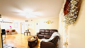 A living room with a brown leather sofa, a coffee table, and a dining area with a table and chairs. - Private 2BR and 1BA Condo in Texas Medical Center Houston - Apartment 6710-2 (Houston)