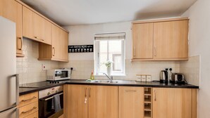 Una cucina moderna con mobili in legno, un frigorifero in acciaio inox, un forno a microonde e un lavello.
