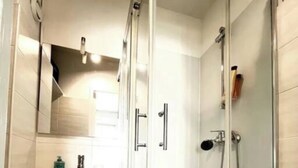 A modern bathroom with a glass shower enclosure, a white vanity with a mirror, and a towel rack. - Studio Lumière du Centre - Parking - Romans (Romans-sur-Isère)