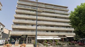 A multi-story hotel with outdoor seating and a visible restaurant. - Studio Lumière du Centre - Parking - Romans (Romans-sur-Isère)