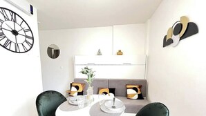A modern dining area with a round table, two chairs, and a sofa with cushions. - Studio Lumière du Centre - Parking - Romans (Romans-sur-Isère)