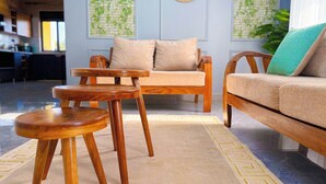 A living room with a sofa, two wooden chairs, a patterned rug, and decorative wall art. - Charming apartment in Kampala for a relaxing getaway (Kampala)