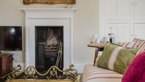 Un salon avec une cheminée, un téléviseur et un canapé à rayures.