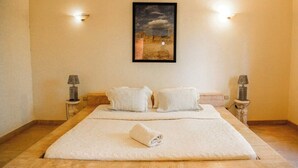 Ein Hotelzimmer mit einem großen Bett, zwei Nachttischen mit Lampen und einem gerahmten Bild an der Wand.