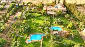 Eine Vogelperspektive eines Resorts mit mehreren Schwimmbecken, üppiger Vegetation und einem großzügigen Gebäude mit flachem Dach.