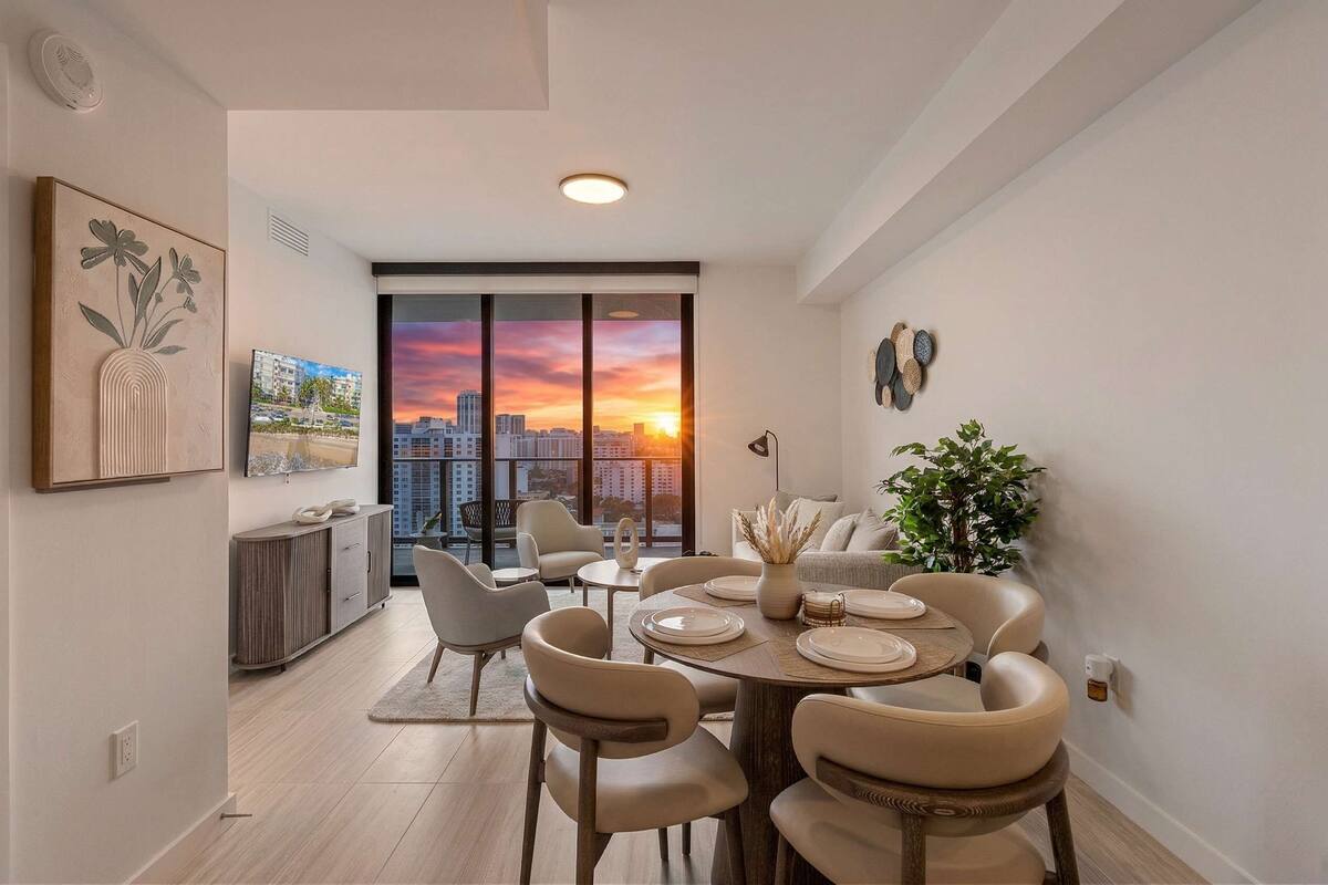A dining area with a city view, modern furniture, and a large window.