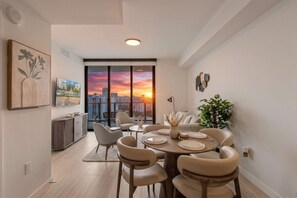 A dining area with a city view, modern furniture, and a large window. - 72 Building Miami Beach Condo - We Host (Miami Beach)