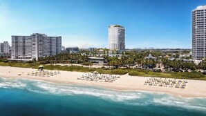 A coastal cityscape with high-rise buildings, a beach with umbrellas, and a clear sky. - Elegant Miami Beach Condos (Miami Beach)