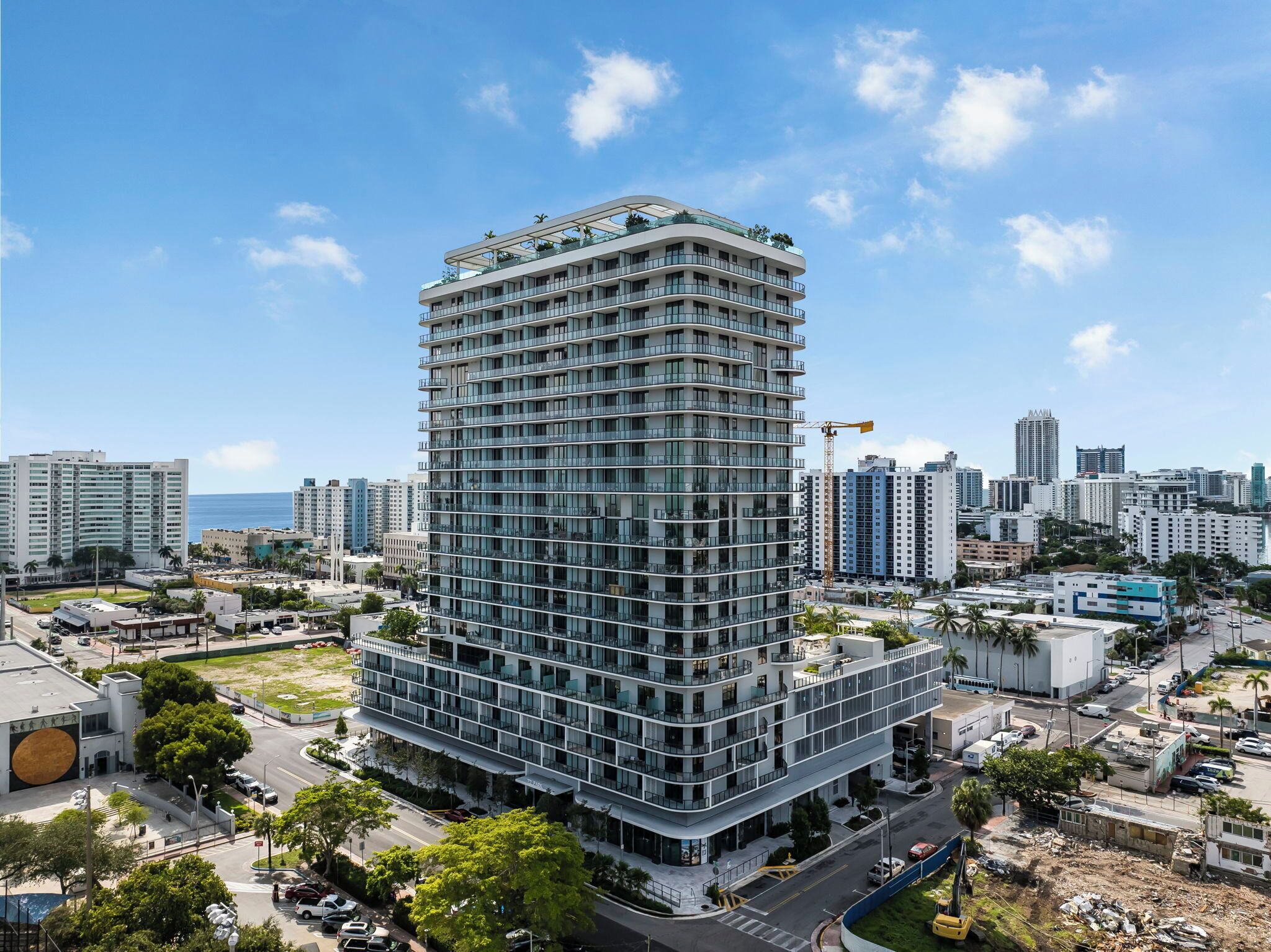 Un immeuble moderne de grande hauteur, doté de nombreux balcons, entouré d’autres immeubles de grande hauteur et surplombant un ciel dégagé.