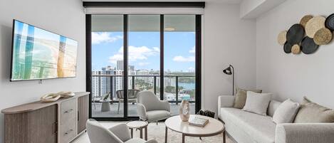 A modern living room with a large window, a flat-screen TV, and a city view.