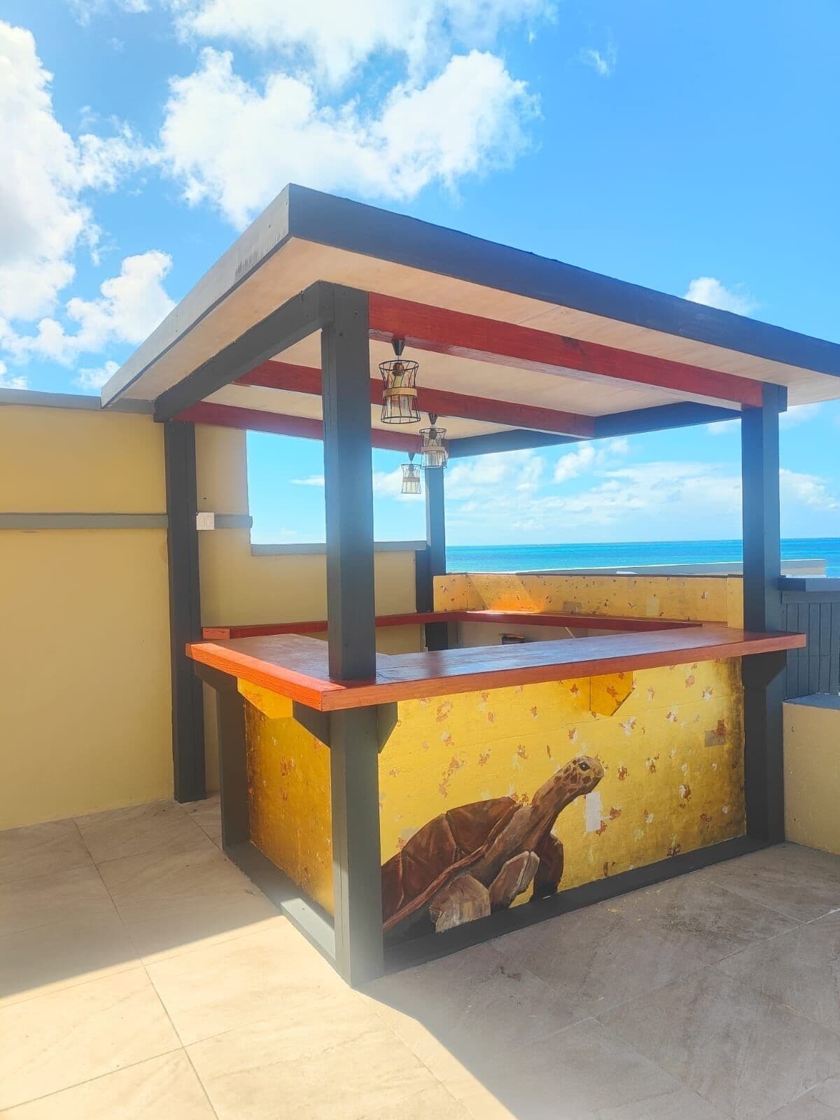 A beachside bar with a wooden counter and a mural of a turtle.