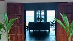 A room with a view of the ocean, a sofa, and two large potted plants. - Turtle Cove House by Le Haus (St. John's)