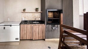 A compact kitchen with a built-in refrigerator, wooden cabinets, and a black oven. - Cozy Apartment for 2 (between CGH and Interlagos) (São Paulo)