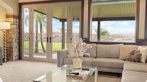 A living room with a beige sofa, a glass coffee table, and a stone accent wall. - Luxe 5BR Villa / Event-Friendly & Pool Table (Temecula)