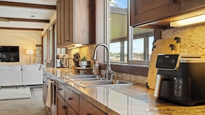 A modern kitchen with a large window, stainless steel appliances, and wooden cabinets. - Luxe 5BR Villa / Event-Friendly & Pool Table (Temecula)