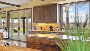 A modern kitchen with wooden cabinets, a granite countertop, and a view of the outdoors. - Luxe 5BR Villa / Event-Friendly & Pool Table (Temecula)