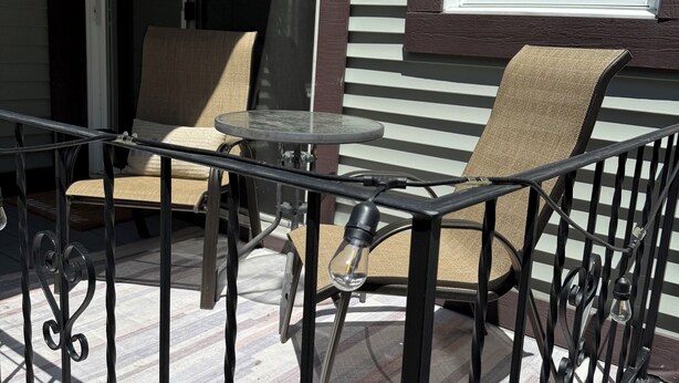 A patio with a table and two chairs, a sliding glass door, and a window with blinds.