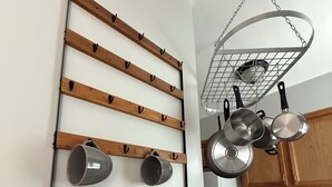 A kitchen with a wooden utensil rack holding mugs and a hanging pot rack with cookware.