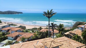Una zona costera con edificios de techo de teja terracota, una palmera y una playa.