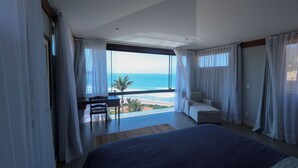 Un dormitorio con una cama grande, vistas al océano y un balcón con mesa y sillas.