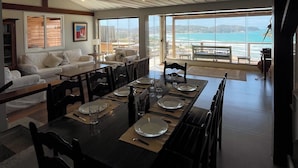 Un comedor amplio con una mesa larga dispuesta para seis personas, con vistas a un paisaje marino.