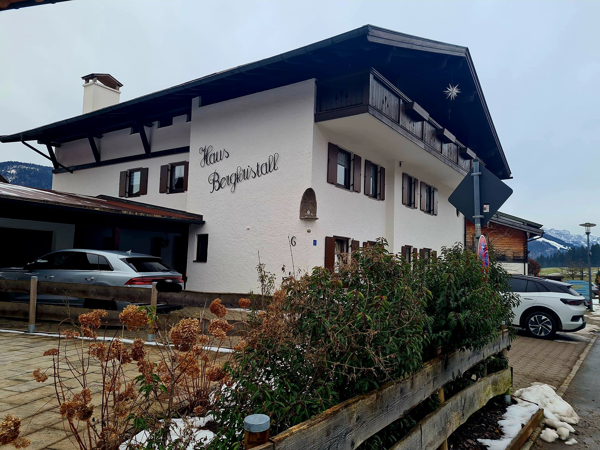 A white building with the sign "Haus Bergkristall" and a balcony.