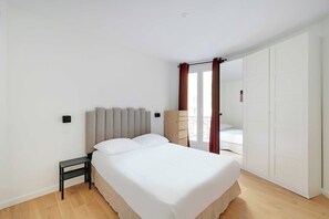Un dormitorio con cama, mesita de noche, armario y vistas a un balcón.