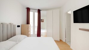 A bedroom with a bed, a wardrobe, a TV, and a door leading to another room. - Superb apt A/C - 2br/6p - St Germain-des-pres (Paris)