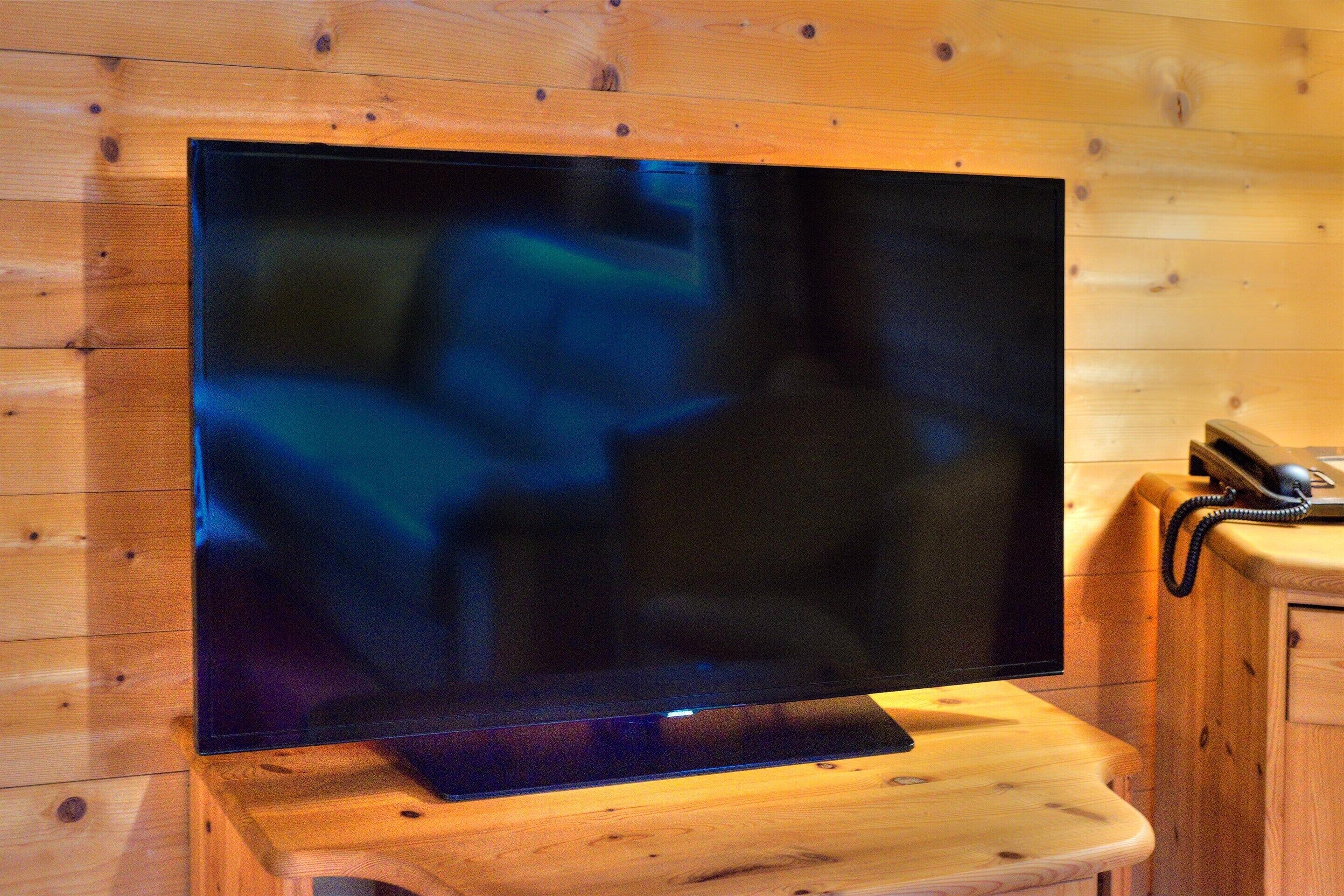 A television mounted on a wooden stand in a room with wooden walls.