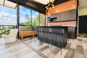 A modern kitchen with a bar area, large windows, and a view of the outdoors.
