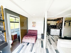 Ein modernes Wohnzimmer mit einer Couch, einem Essbereich mit einer Küche im Hintergrund und einem gemusterten Boden.