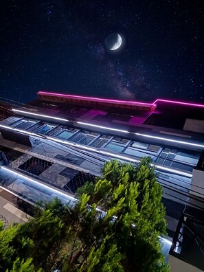 Un edificio moderno con fachada de vidrio y una franja de neón rosa.
