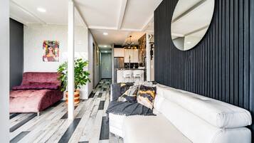 Un salon moderne avec un canapé, un fauteuil rouge et une plante en pot.