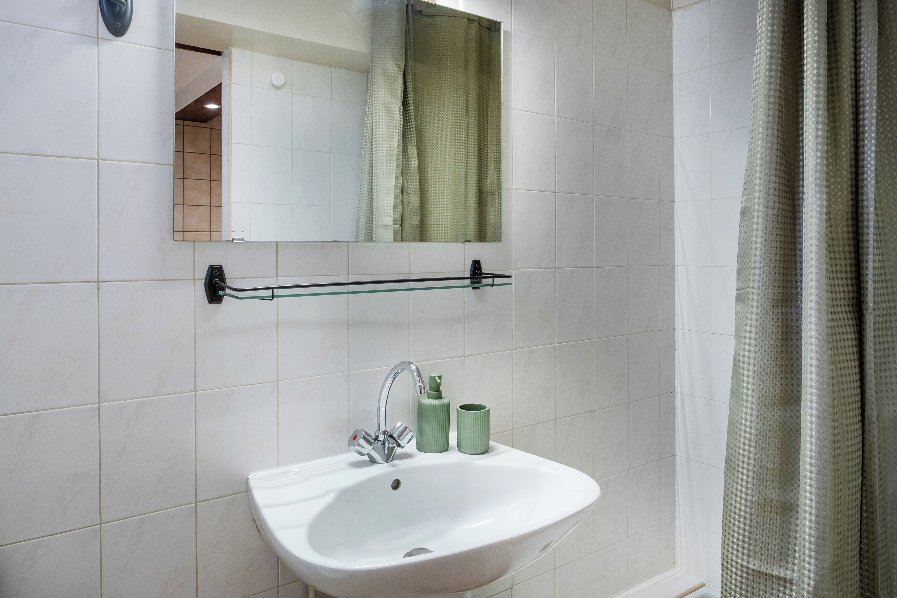 Un baño con lavamanos blanco, un espejo y una cortina de ducha.