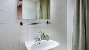 Un baño con lavamanos blanco, un espejo y una cortina de ducha.