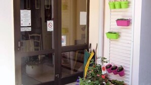 A hotel entrance with a sign reading "ENTREE de l'HOTEL" and a potted plant with flowers in front. - Hotel des Touristes (Pierrefitte-Nestalas)