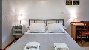 A neatly made bed with white linens and two folded towels at the foot of the bed. - Hotel des Touristes (Pierrefitte-Nestalas)