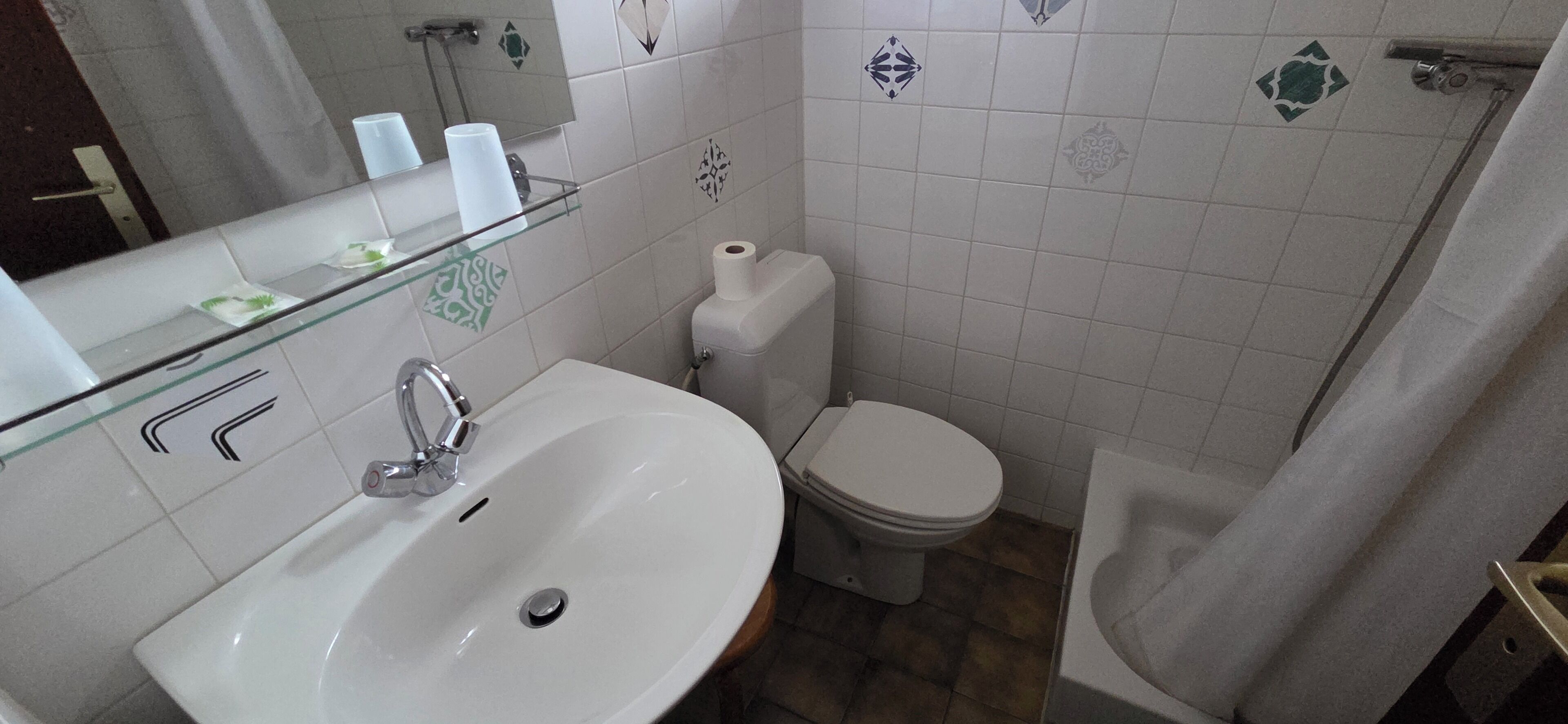 A small bathroom with a white sink, toilet, and shower.