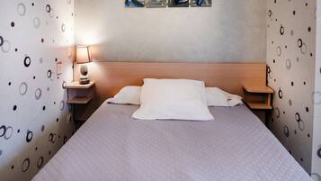 A neatly made bed with white bedding, a wooden headboard, and a bedside table with a lamp.